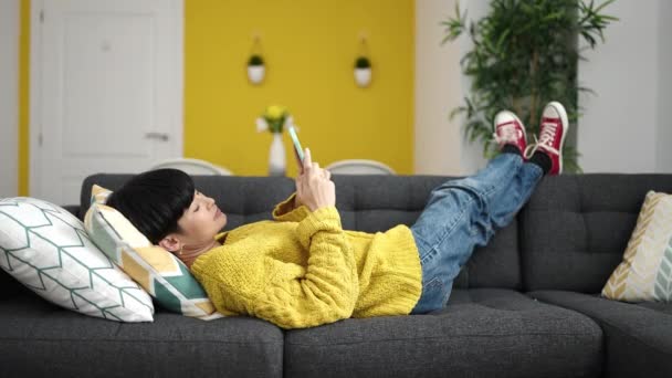 Joven Mujer China Usando Teléfono Inteligente Tumbado Sofá Casa — Vídeos de Stock