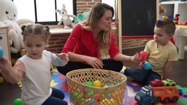 Lärare Med Pojke Och Flicka Leker Med Bollar Sittande Golvet — Stockvideo