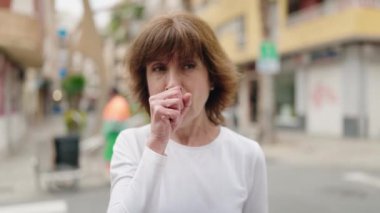 Middle age woman coughing at street