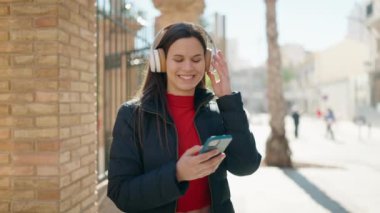 Sokakta müzik dinlerken kendinden emin gülümseyen genç bir kadın.