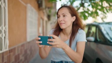 Young woman smiling confident making photo by the smartphone at street
