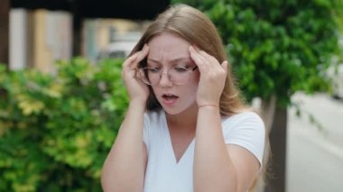 Sokakta baş ağrısı çeken genç sarışın kadın.