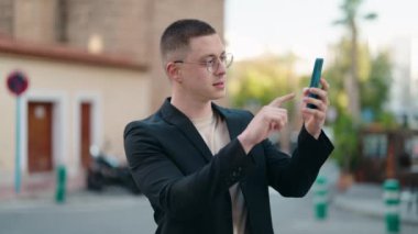 Genç İspanyol yönetici caddedeki akıllı telefonun yanında selfie çekiyor.