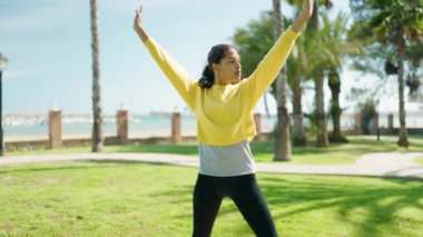 Genç Afrikalı Amerikalı kadın parkta yoga eğitimi alıyor.