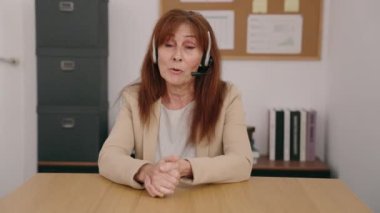 Middle age woman call center agent smiling confident working at office