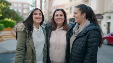 Anne ve kızları gülümsüyor. Kendilerine güveniyorlar. Akıllı telefondan özçekim yapıyorlar.