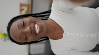 Afro-Amerikalı bir kadın evdeki koltukta video görüşmesi yapıyor.