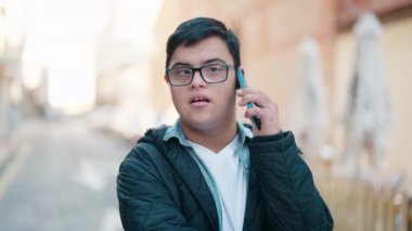 Down sendromlu adam caddedeki akıllı telefondan konuşuyor.