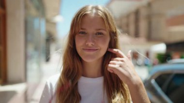 Young blonde girl smiling confident wearing glasses at street