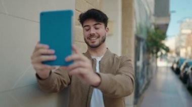 Young hispanic man smiling confident having video call at street