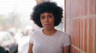 Sokakta ciddi bir ifadeye sahip Afro-Amerikalı genç bir kadın bekliyor.