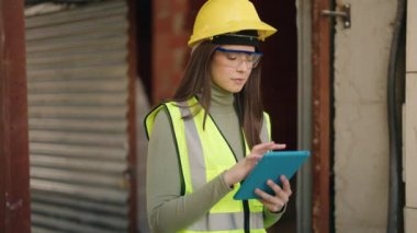 İnşaat alanında dokunmatik ped kullanan genç İspanyol kadın mimar.