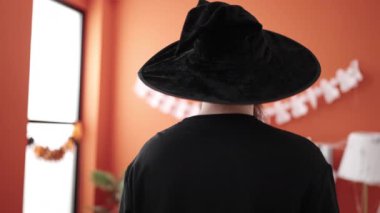 Young redhead man wearing wizard costume doing scare expression at home