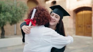 İki kadın anne ve kız, kampüs üniversitesinde birbirlerine sarılıyorlar.