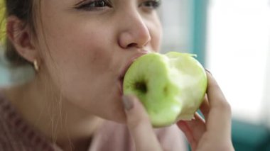 Kütüphanede yeşil elma yiyen genç, güzel İspanyol kadın.