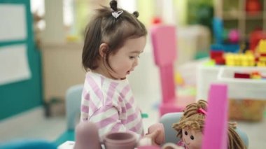Anaokulunda oyuncak bebekle oynayan sevimli Çinli çocuk.