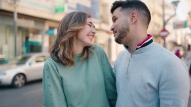 Young couple smiling confident doing heart symbol with hands at street