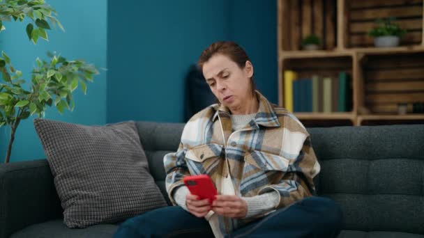 自宅で勝者の表情を持つスマートフォンを使用している中年女性 — ストック動画