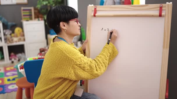 Jovem Chinesa Professora Pré Escolar Sentada Cadeira Escrevendo Quadro Jardim — Vídeo de Stock