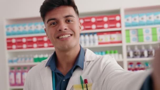 若いですヒスパニック系の男薬剤師持っていますビデオ通話で薬局 — ストック動画