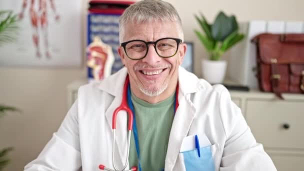中年白发男子医生坐在桌子上 微笑着在诊所里 — 图库视频影像