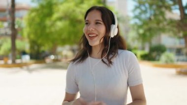 Parkta müzik dinleyip dans eden kendine güvenen genç bir kadın.