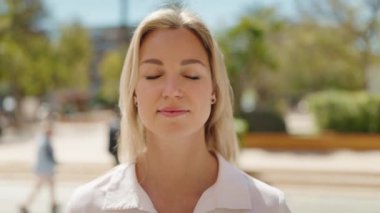 Parkta kendinden emin gülümseyen genç sarışın kadın.