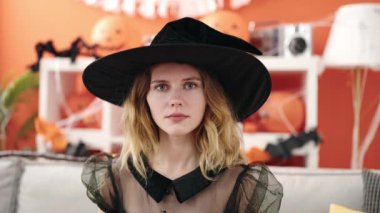 Young blonde woman wearing halloween costume sitting on sofa at home