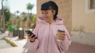Genç İspanyol kadın akıllı telefon kullanıyor, sokakta kahve içiyor.