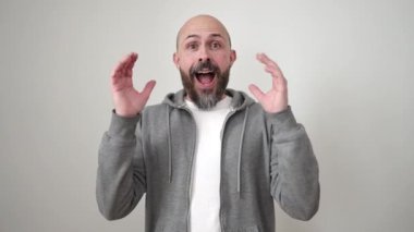 İzole edilmiş beyaz arka planda sürpriz bir ifadeyle duran genç kel adam.