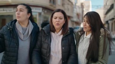 Anne ve kızları sokakta şehir haritasını kullanarak gülümsüyor.