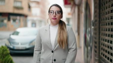 Sokakta kollarını kavuşturmuş genç bir kadın yönetici.