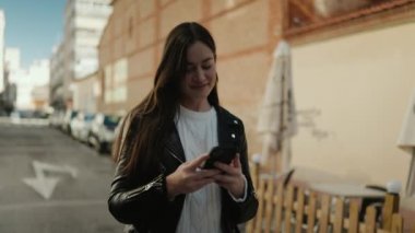 Sokakta akıllı telefon kullanan, kendine güvenen genç İspanyol kadın.