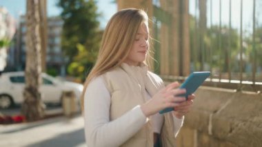 Sokakta dokunmatik ped kullanan kendine güvenen genç sarışın kadın.