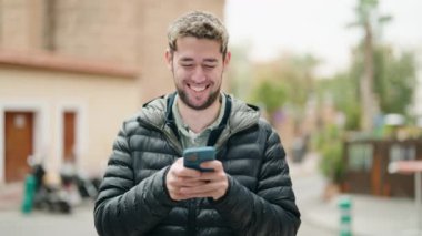 Sokakta akıllı telefon kullanan kendine güvenen genç adam.