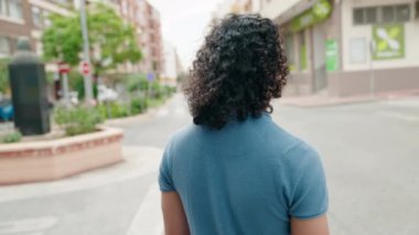 Sokakta kollarını kavuşturmuş genç Latin bir adam.