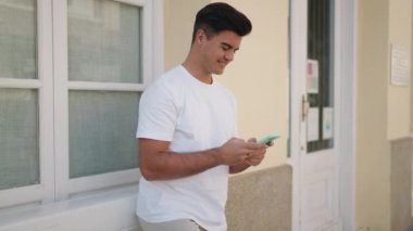 Sokakta akıllı telefon kullanan, kendine güvenen genç bir İspanyol.