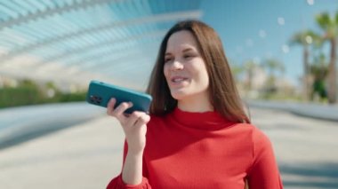 Young woman talking on the smartphone walking at park
