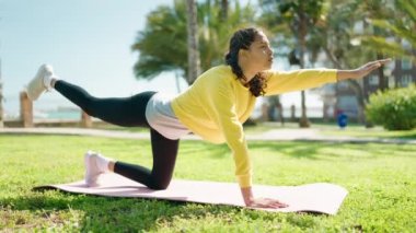 Genç Afrikalı Amerikalı kadın parkta yoga eğitimi alıyor.