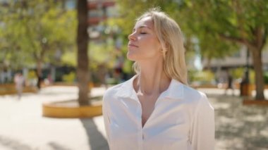 Young blonde woman smiling confident breathing at park