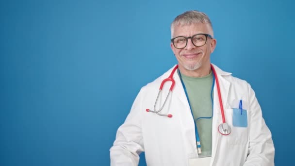Μεσήλικας Γκριζομάλλης Γιατρός Χαμογελαστός Αυτοπεποίθηση Παρουσιάζοντας Πάνω Από Απομονωμένο Μπλε — Αρχείο Βίντεο