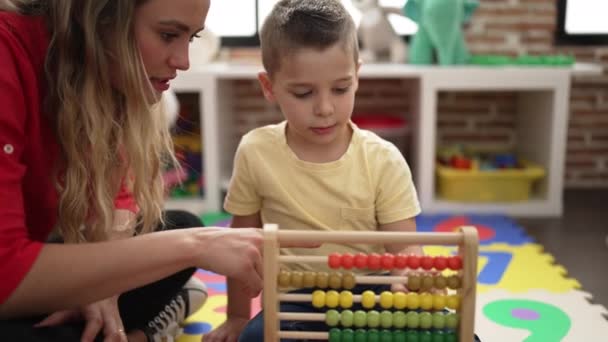 教師と幼児は数学を学び そろばんは幼稚園の床に座っています — ストック動画
