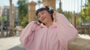 Young hispanic woman smiling confident listening to music and dancing at street