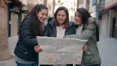 Anne ve kızları sokakta şehir haritasını kullanarak gülümsüyor.