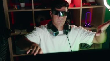 Oyun odasında sanal gerçeklik gözlüğü kullanarak video oyunu oynayan İspanyol asıllı genç adam.