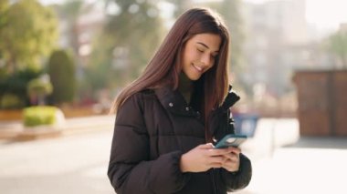 Sokakta akıllı telefon kullanan, kendine güvenen genç İspanyol kadın.