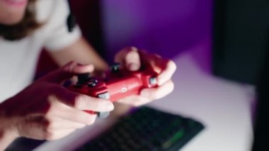 Young beautiful hispanic woman streamer playing video game using joystick at gaming room