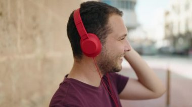 Sokakta müzik dinlerken kendinden emin gülümseyen genç adam.