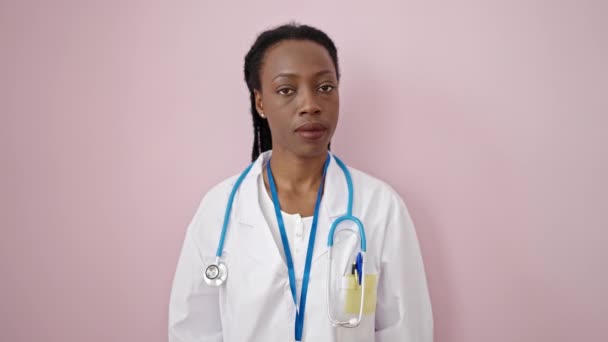 非洲裔美国女医生没有用手指在孤立的粉色背景上做任何手势 — 图库视频影像