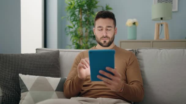 Jonge Spaanse Man Met Touchpad Zittend Bank Thuis — Stockvideo